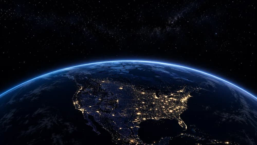The earth at night from orbit, city lights spread across the continents